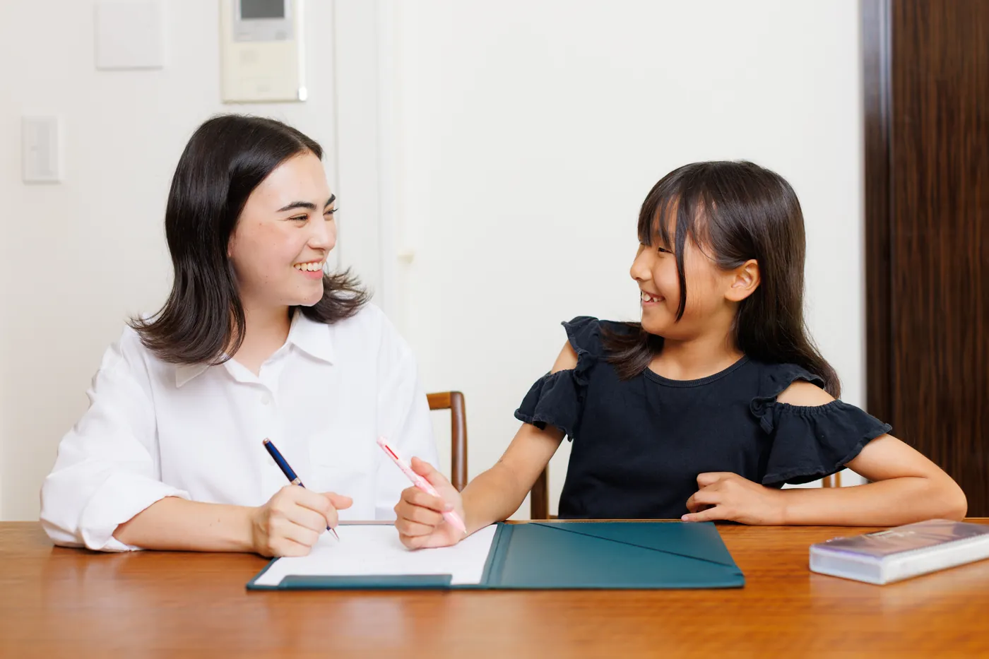 CareFinder sitter and a young girl smiling at each other at a table