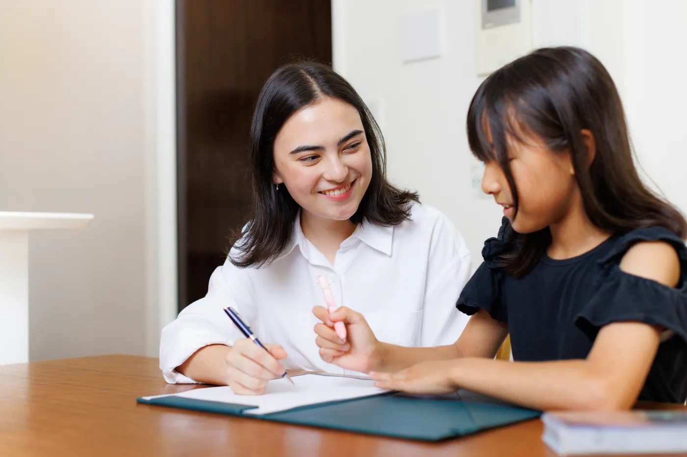 CareFinder sitter helping a schoolgirl with homework at a table