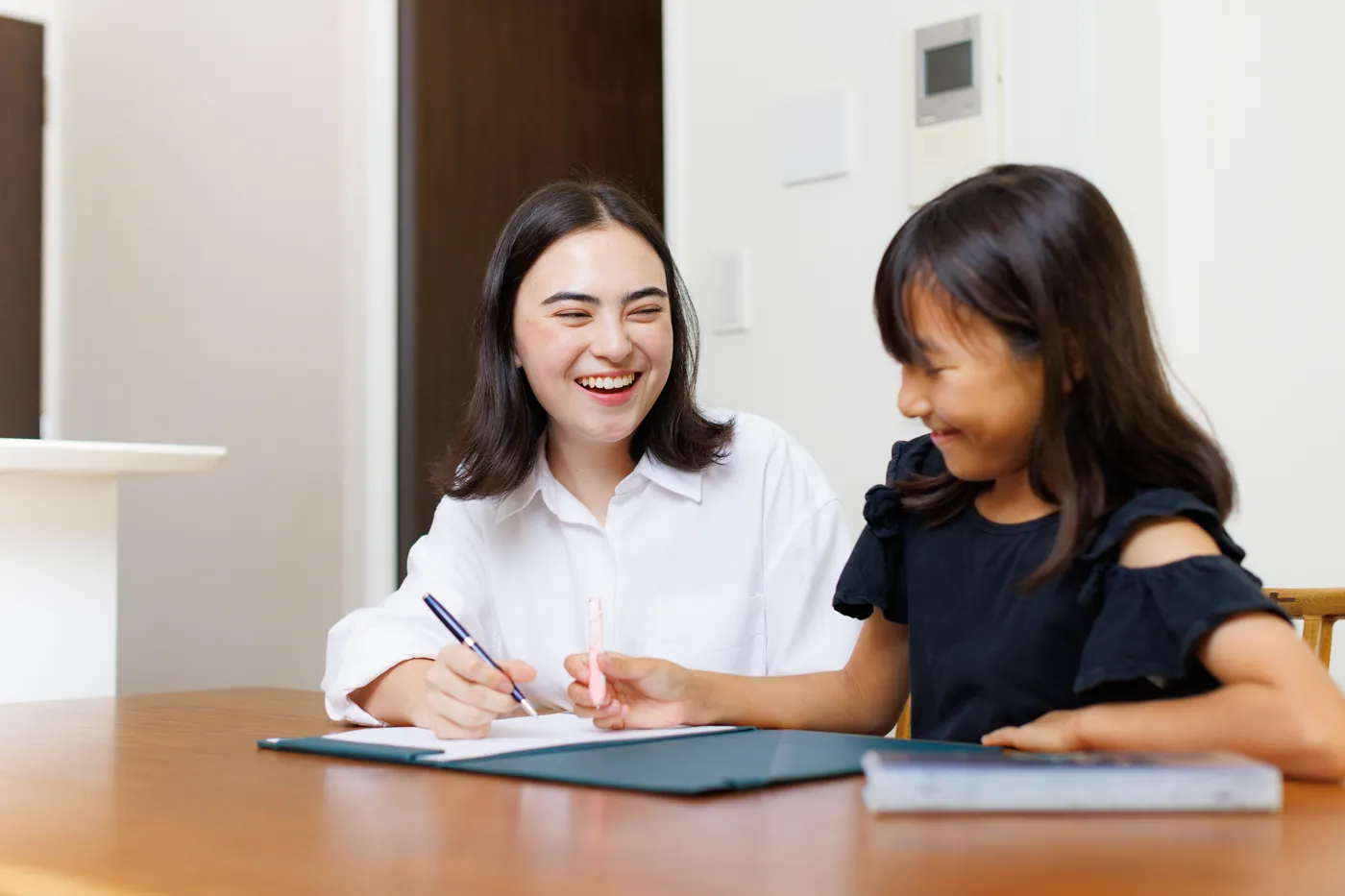 CareFinder sitter keeping a young girl engaged with writing practice at the table
