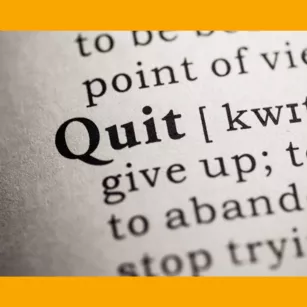 Close-up on dictionary text for the word "quit" surrounded by orange border.