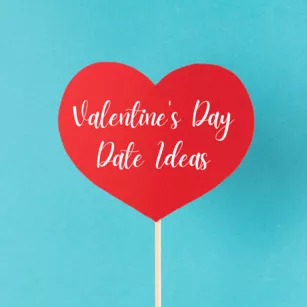 a light blue background with a red paper heart on a wooden stick. White words in cursive read "Valentine's Day Date Ideas"